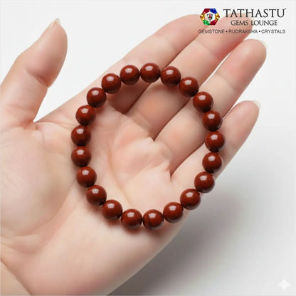 Authentic Original Red Jasper Bracelet at Tathastu Gems Lounge held on an open palm displaying rich opaque brick-red gemstone beads.