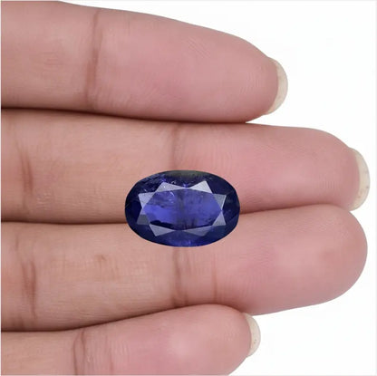 Natural oval facet cut Blue Iolite Neeli stone held in fingers showing deep blue color - Tathastu Gems